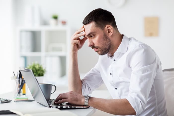 Haarausfall durch Stress - Gestresster Mann arbeitet im Büro