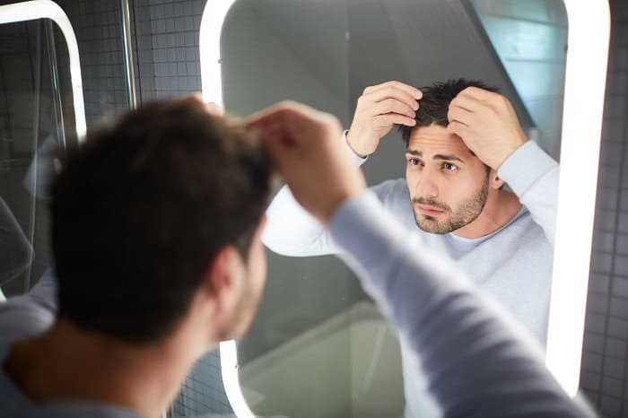 Junger Mann vor dem Siegel gutachtet Haarausfall