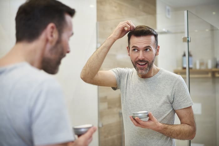 Junger Mann pflegt seine Haare.